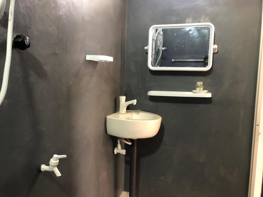 Ein Badezimmer mit einem weißen Waschbecken, einem Spiegel und einem Handtuchhalter.