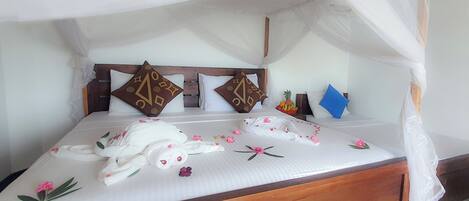 Un lit à baldaquin, des oreillers ornés de motifs géométriques et un petit panier de fruits.
