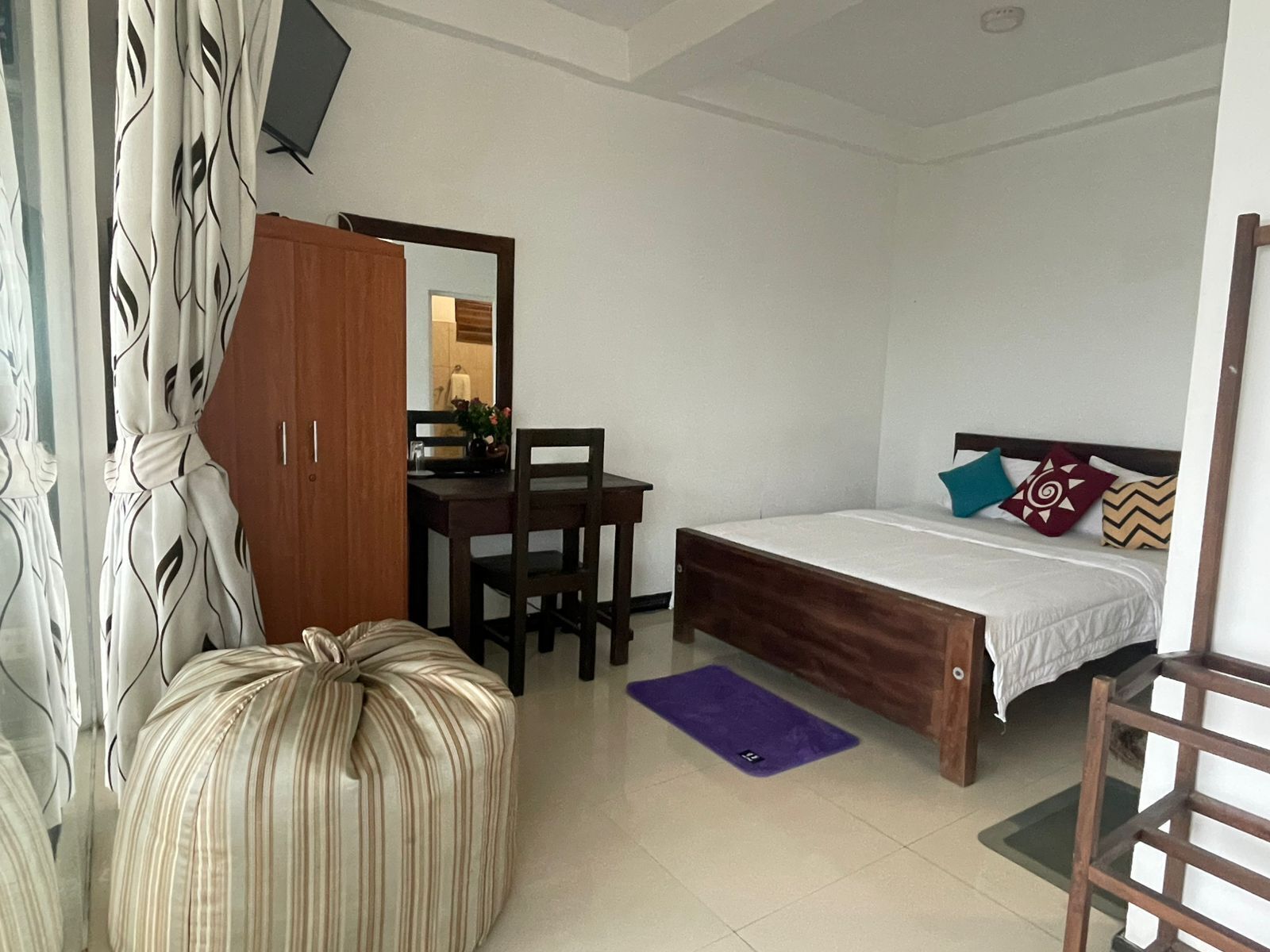 Un dormitorio con cama, escritorio, silla, armario y espejo.
