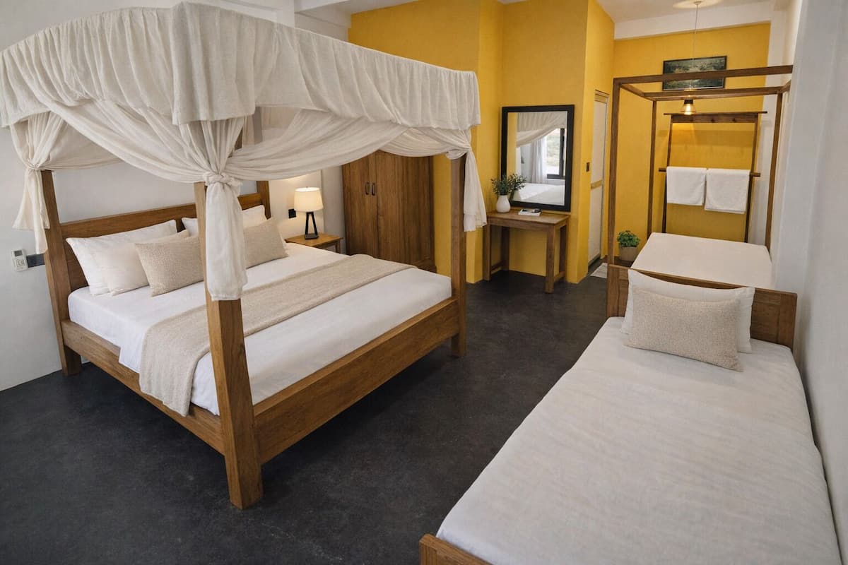 Un dormitorio con cama con dosel, una cama individual, una mesita de noche con lámpara y un espejo.