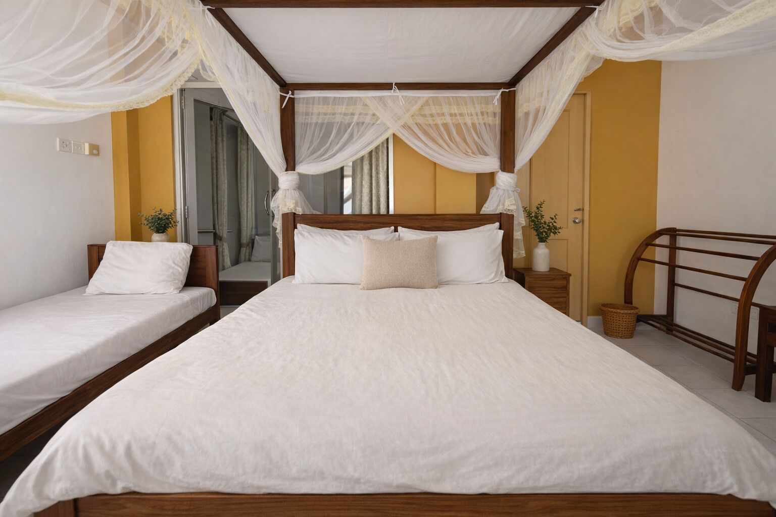 A bedroom with a large bed, two smaller beds, a wooden headboard, and a canopy.