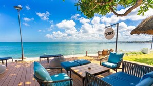 Une terrasse en bois avec des sièges extérieurs, une enseigne indiquant « SOKOIDE » et une vue sur l’océan.