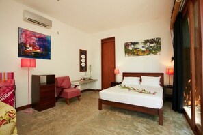 Una habitación de hotel con cama, escritorio, silla y obras de arte en las paredes.