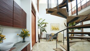 Un interior moderno con una escalera de caracol, un comedor y un ventanal grande.