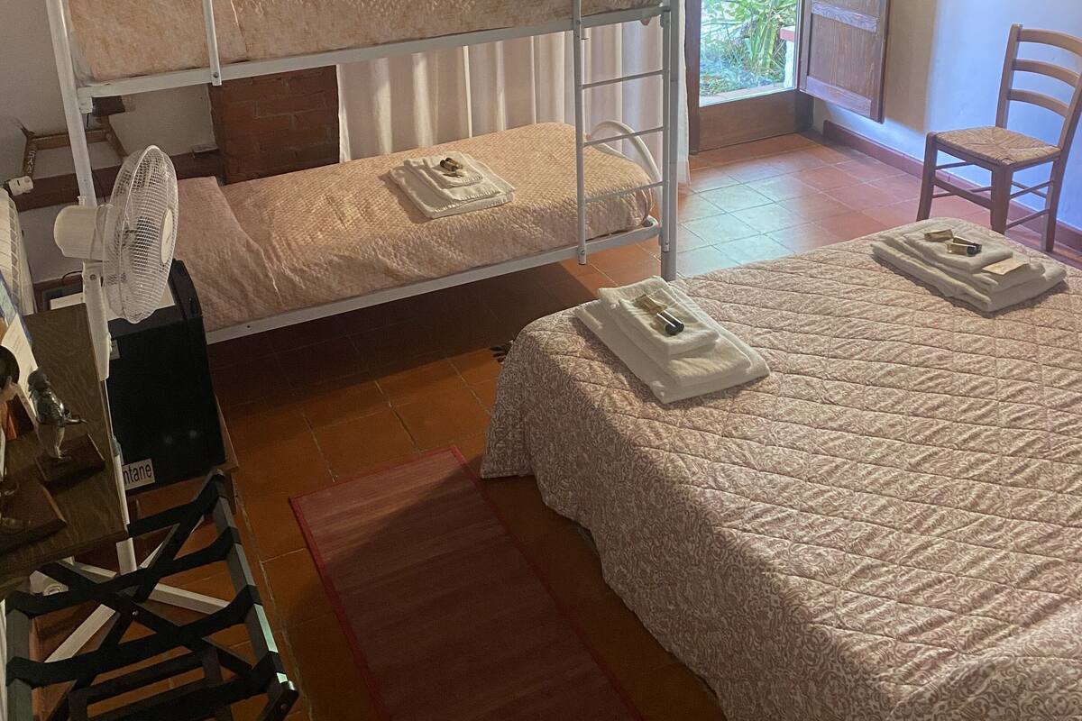 Een kamer met stapelbedden, een ventilator, een stoel en een bed met dekbed.