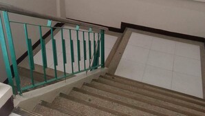 Una escalera con barandales verdes y un rellano con azulejos.