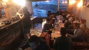 A restaurant with a view of the cityscape, a counter with food items, and patrons dining. - Istanbul Harmony Hostel (Istanbul)