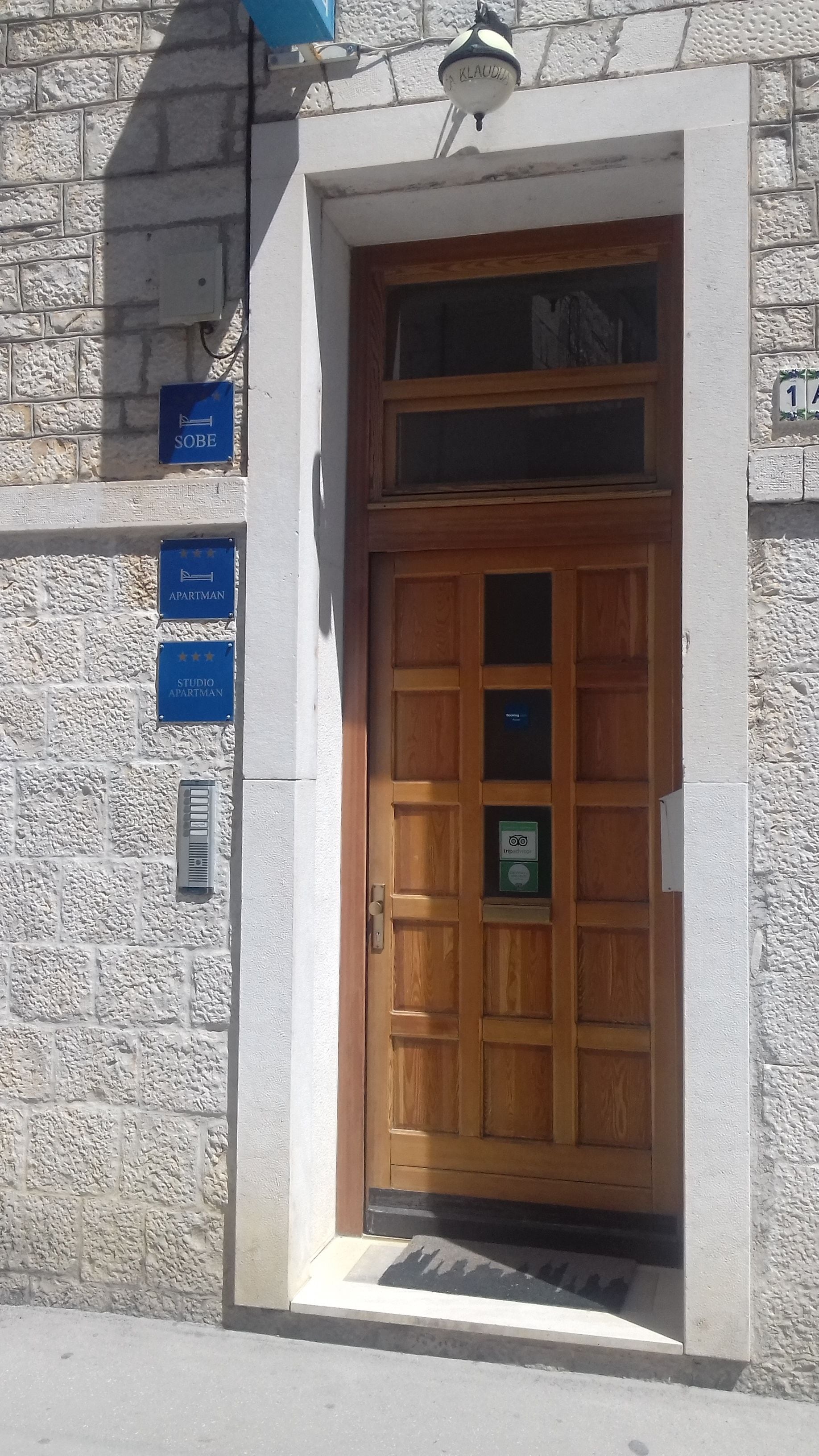 A wooden door with a glass panel, a blue sign reading "SOBE," and a "STUDIO APARTMAN" sign.