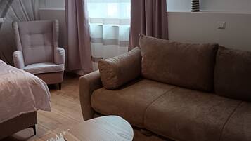 A modern living room with a sofa, armchair, and two small tables.