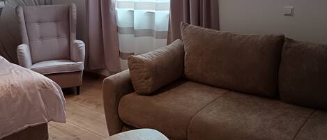 A modern living room with a sofa, armchair, and two small tables.
