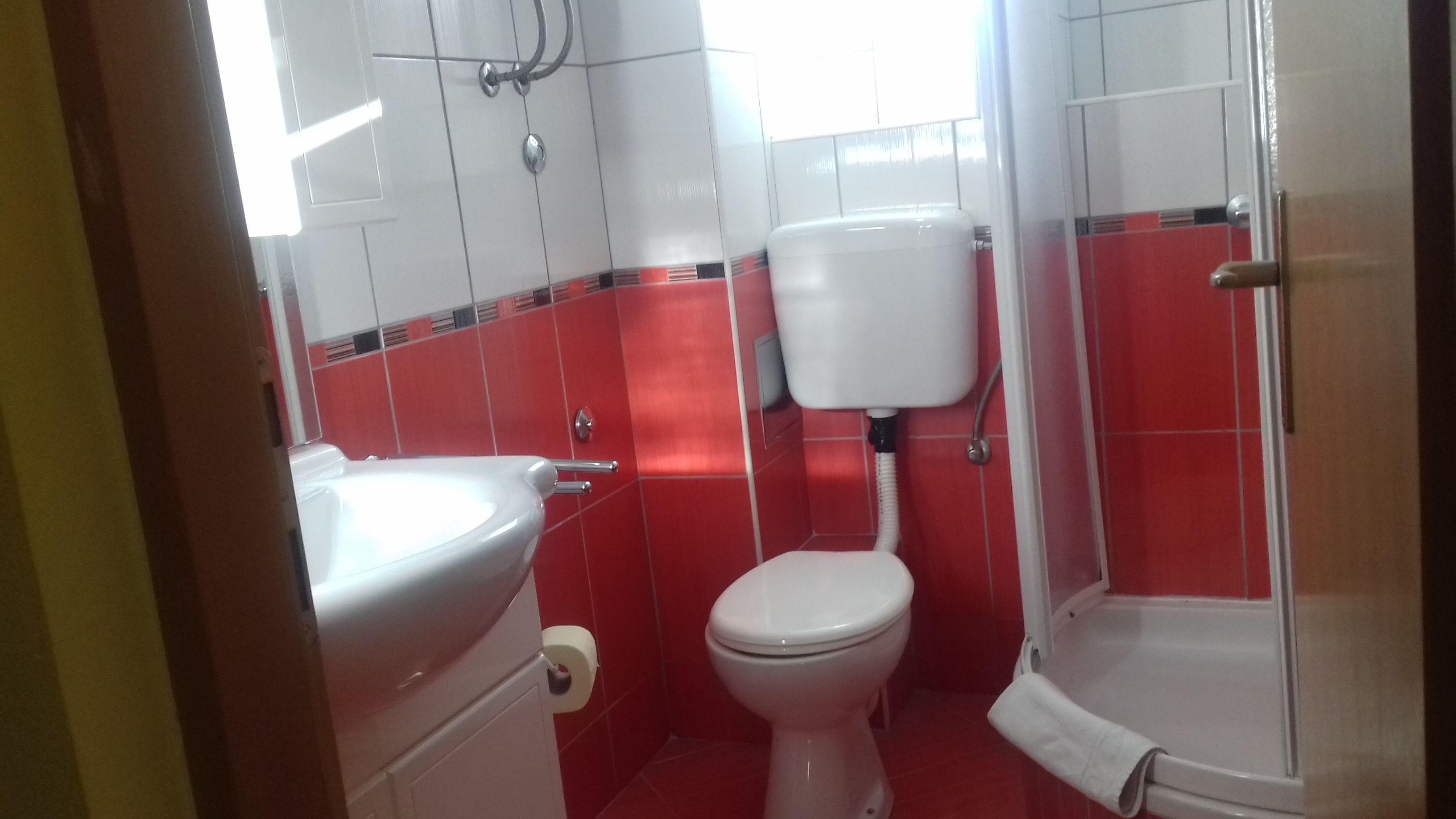 A small bathroom with a toilet, sink, and shower.