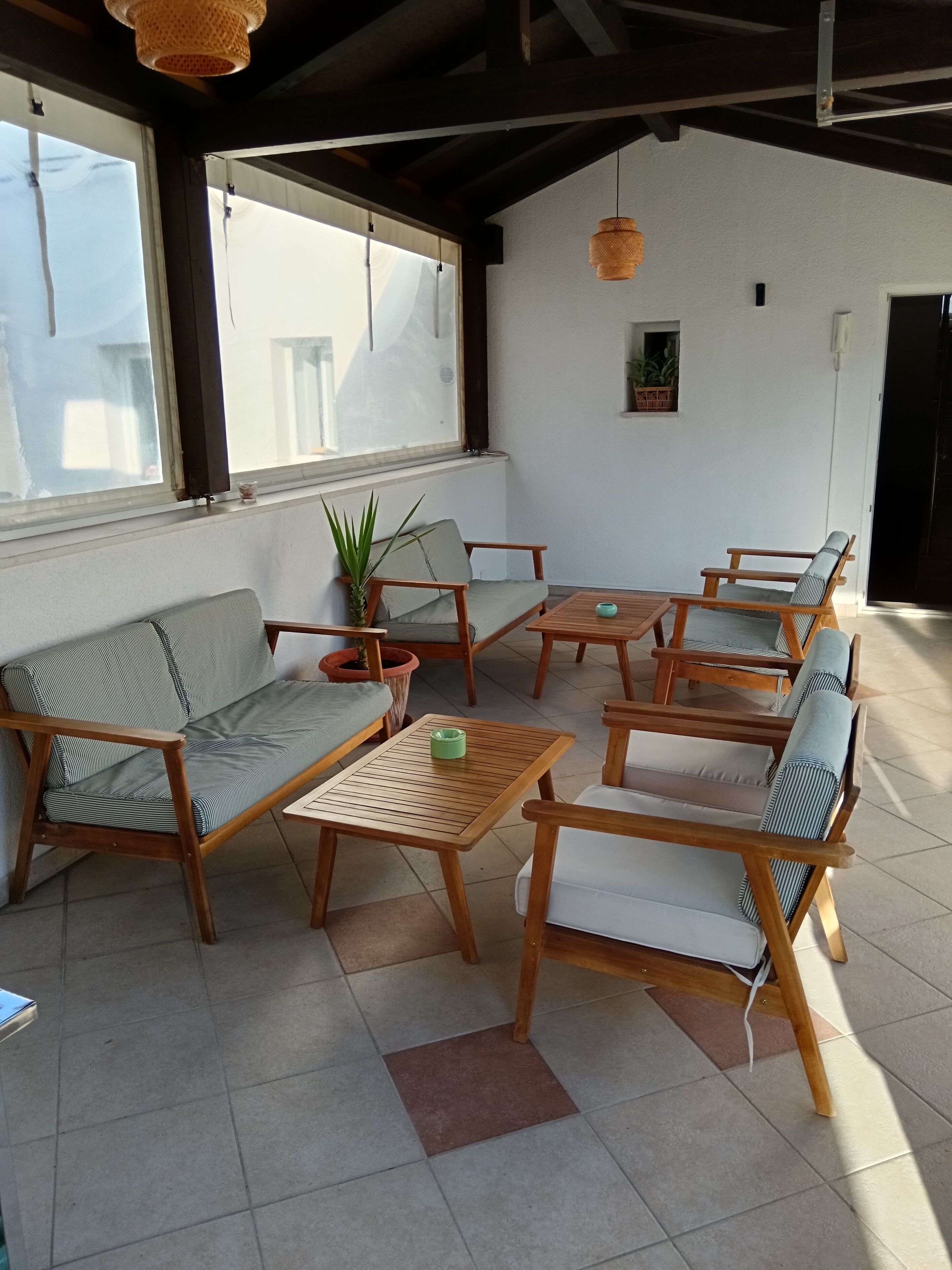 A room with a sofa, chairs, a small table, and a potted plant.