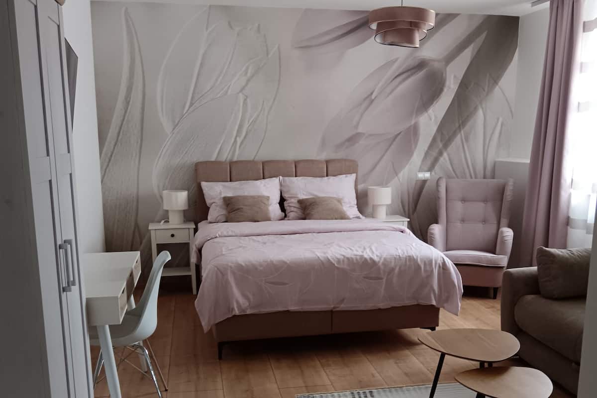 A bedroom with a bed, bedside tables, a chair, a desk, and a wardrobe.