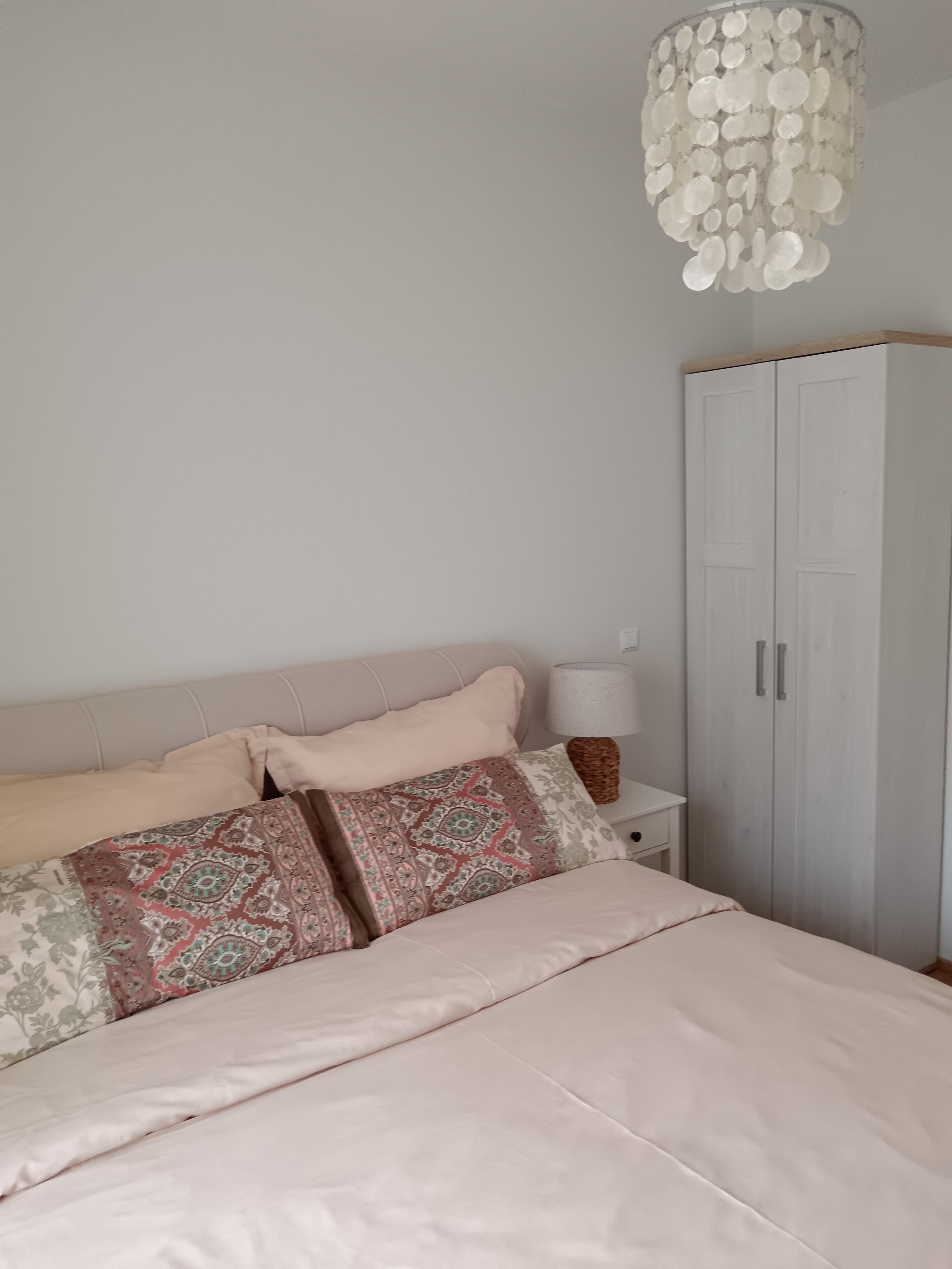 A bedroom with a bed, a wardrobe, and a chandelier.