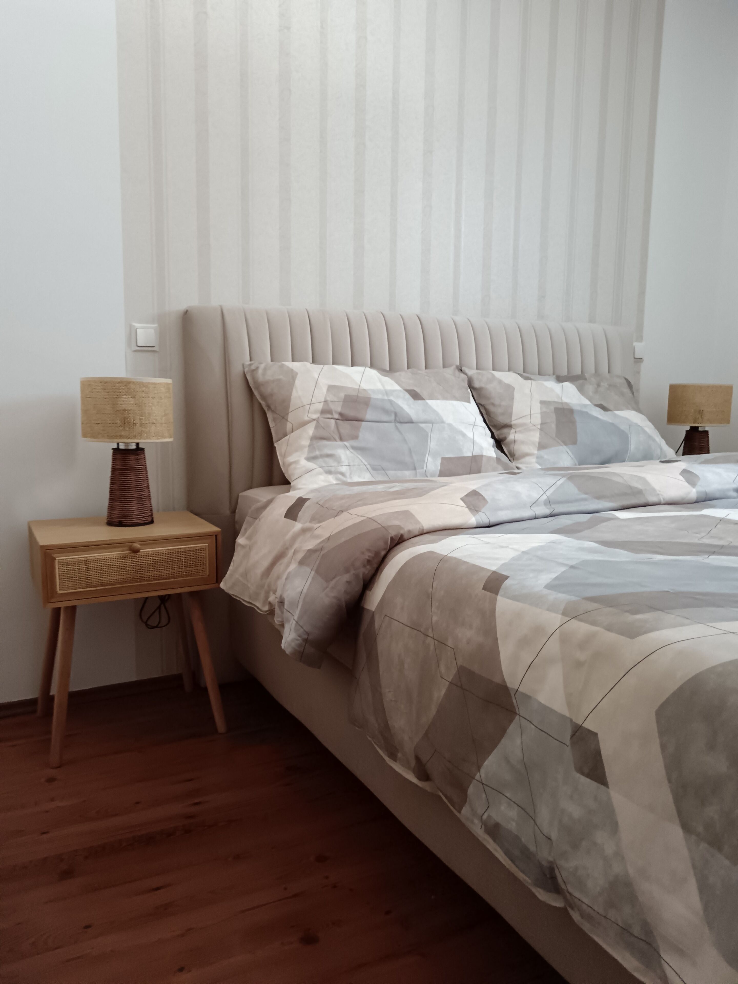 A bedroom with a bed, two bedside tables, and a lamp on each table.