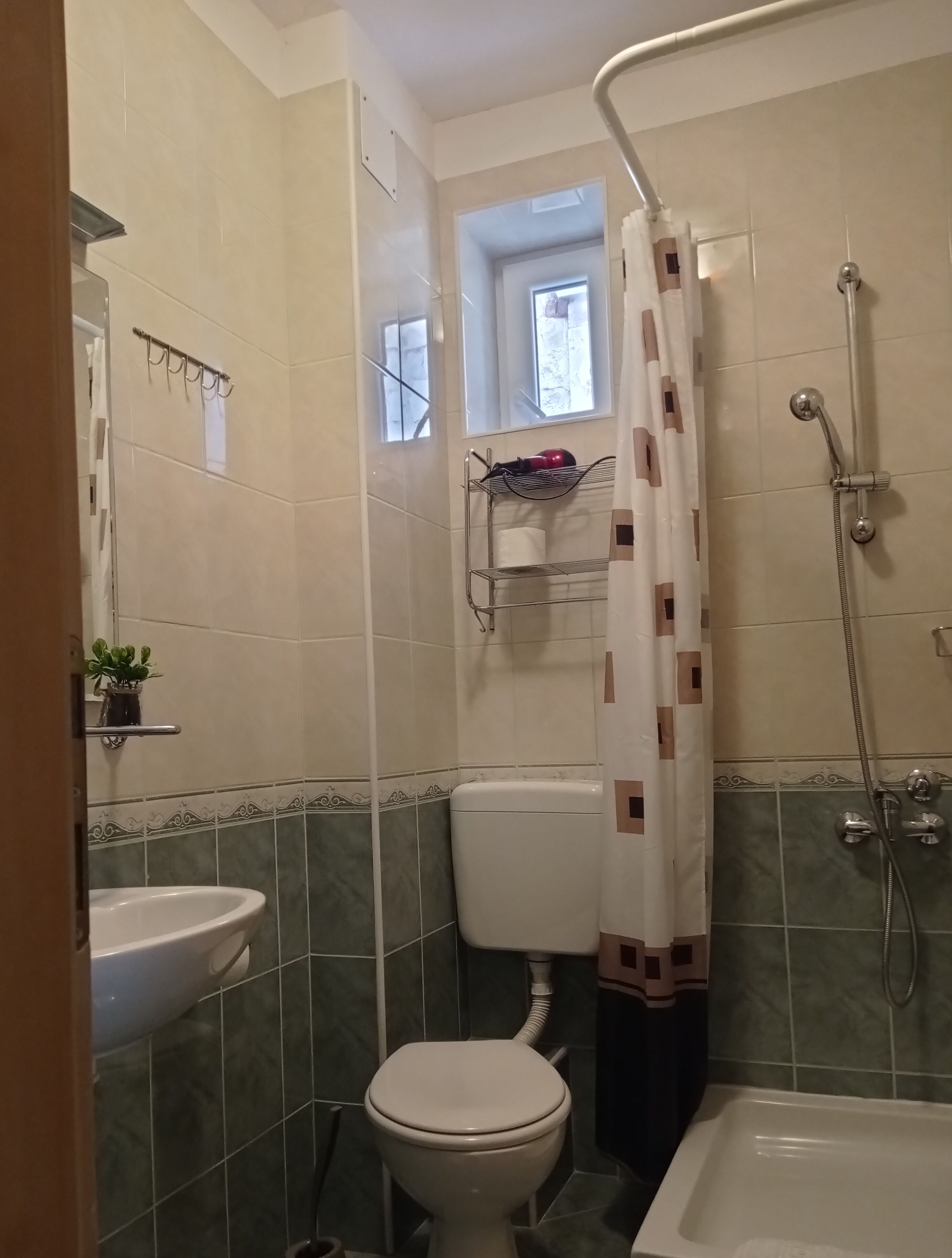Un baño con inodoro, lavabo, ducha y ventana.