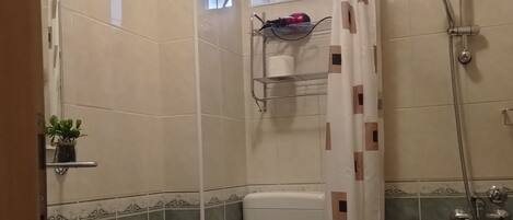 Un baño con inodoro, lavabo, ducha y ventana.