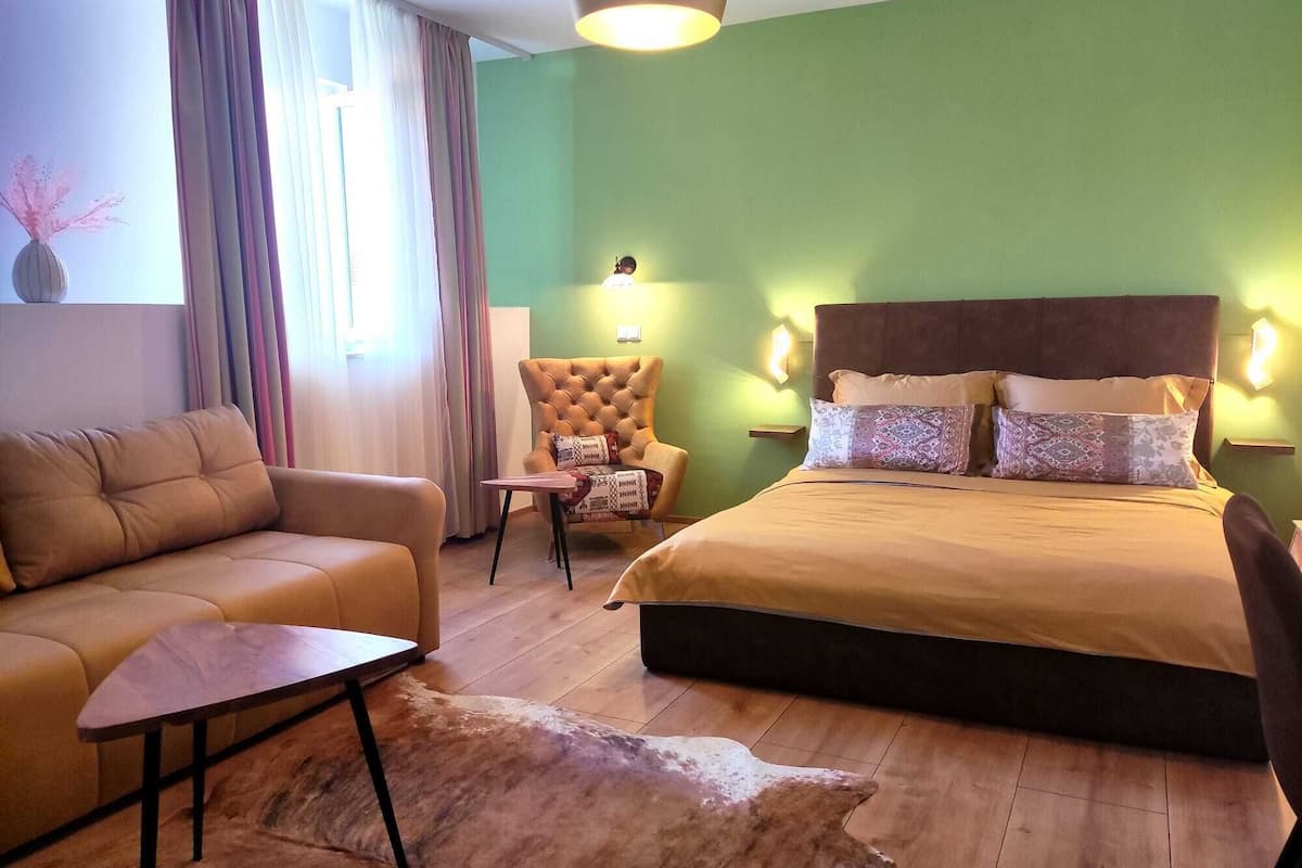 A room with a bed, a sofa, a chair, and a small table.