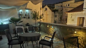 An outdoor patio with a round table and chairs, potted plants, and a view of buildings in the background. - House Klaudija (Trogir)