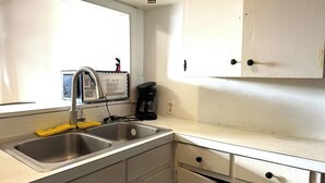 A kitchen with a double sink, a coffee maker, and cabinets.