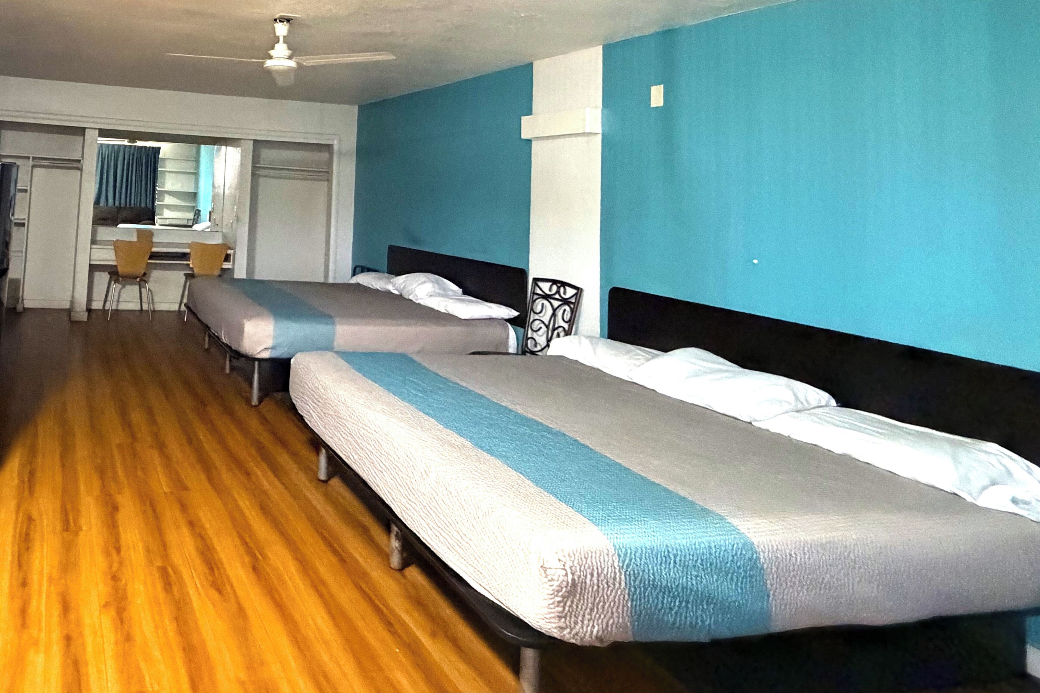 Une chambre avec deux lits simples, un bureau et des chaises.