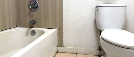 Un baño con bañera, inodoro y pared de madera.