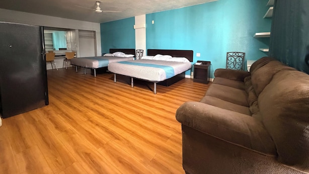 A room with two beds, a couch, a desk, and a window.