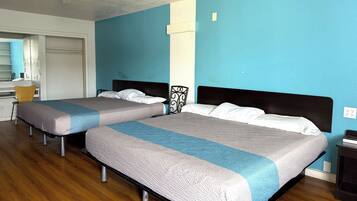 Two single beds with headboards, a wooden floor, a small table, and a chair.