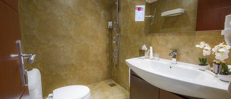 A bathroom with a toilet, sink, and shower.