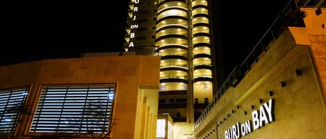 The exterior of the Burj on Bay Hotel with its distinctive cylindrical architecture and illuminated signage.