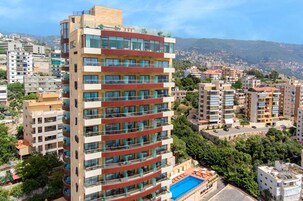 Et hotel med flere etager, altaner, en swimmingpool og udsigt over byens skyline.