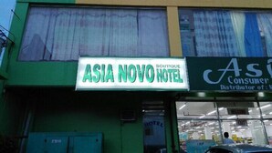 Een gebouw met een bordje voor 'Asia Novo Hotel' en een bordje met de tekst 'Consumenten Distributeur van'.