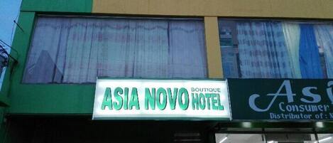A building with a sign for 'Asia Novo Hotel' and a 'Consumer Distributor of' sign.
