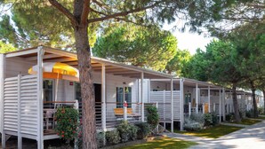 Une rangée de maisons mobiles dotées d’espaces extérieurs aménagés, chacune ayant une véranda couverte et un petit jardin.
