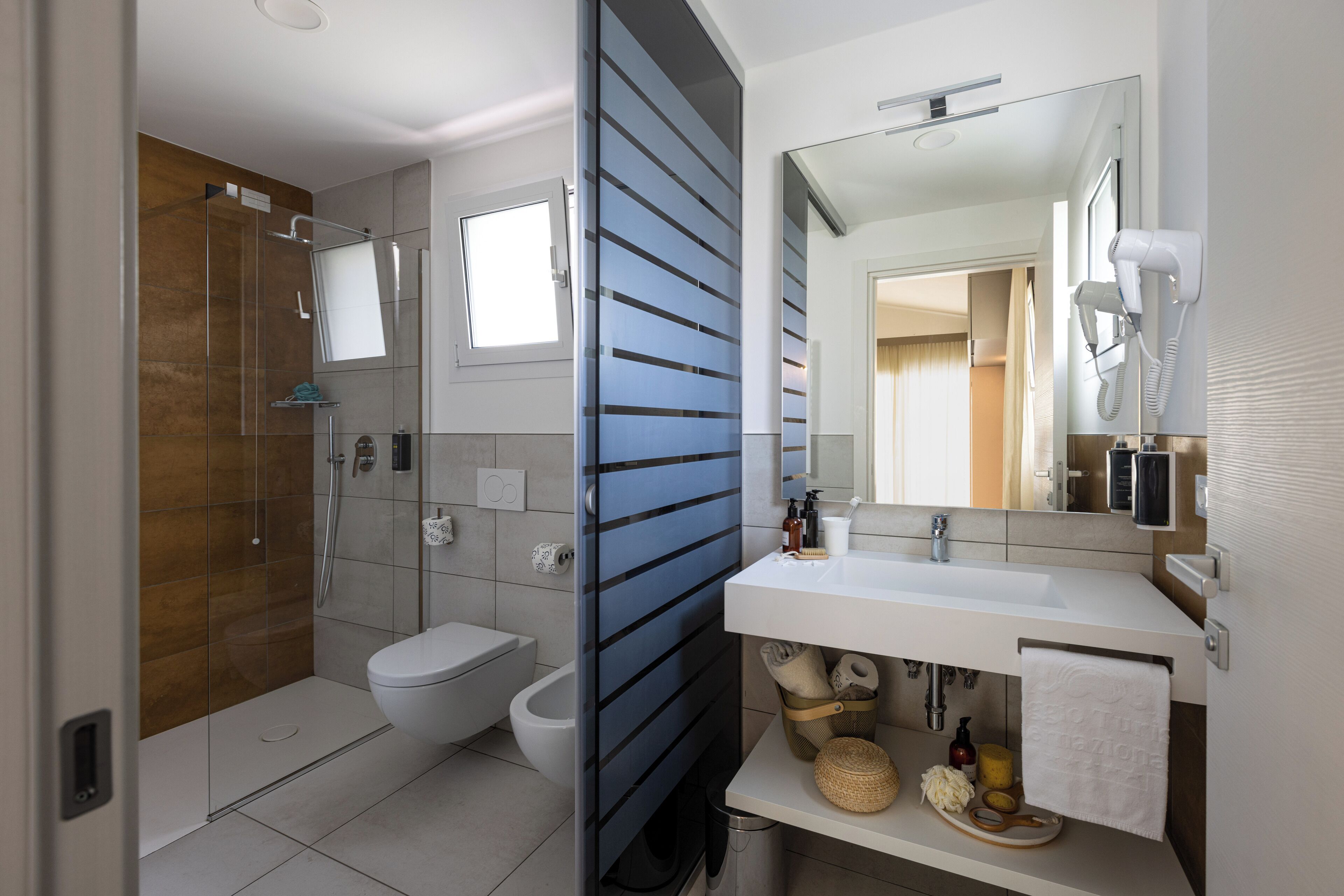 Un baño moderno con ducha de vidrio, inodoro blanco y tocador con espejo.
