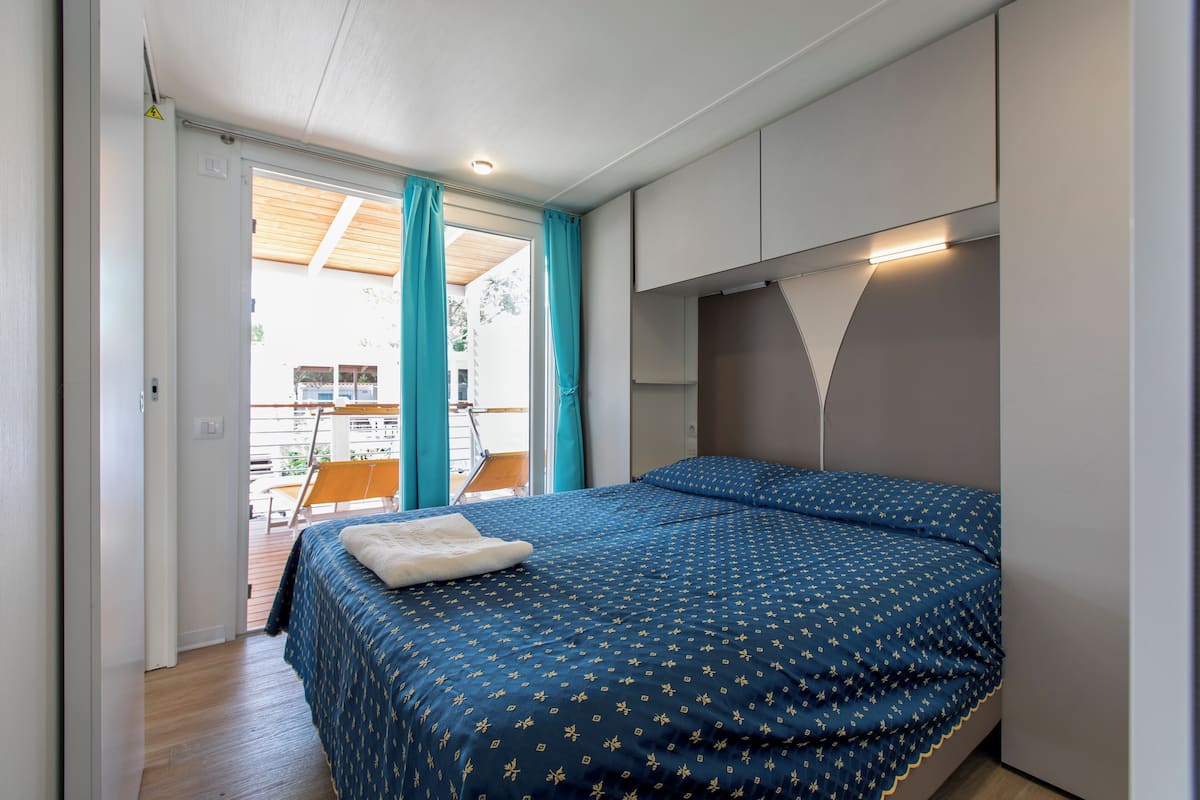 Une chambre à coucher avec un lit, une fenêtre avec des rideaux et une vue sur un espace extérieur.