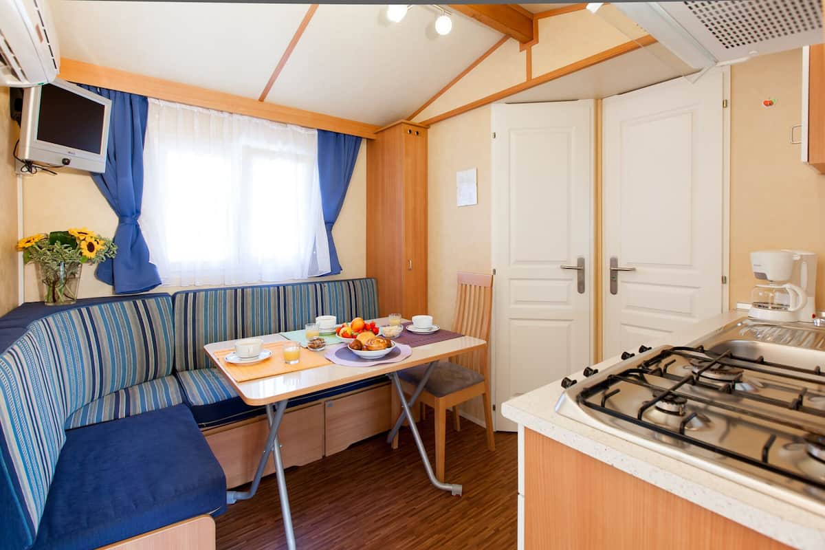 Une cuisine compacte pour camping-car, équipée d’une cuisinière à gaz, d’une table à manger et d’un coin salon avec un canapé.