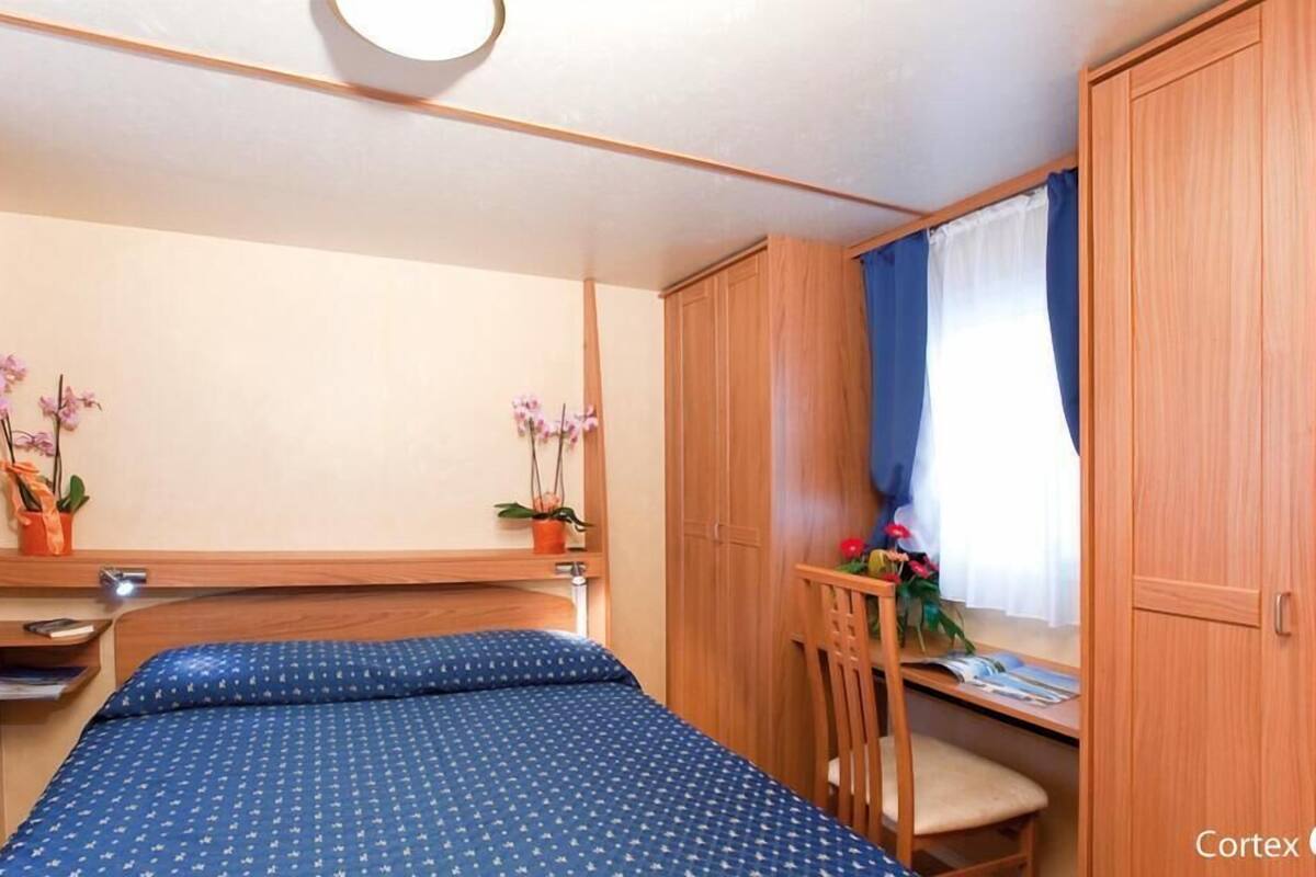 Une chambre à coucher de taille réduite, comprenant un lit, un petit bureau et une armoire.