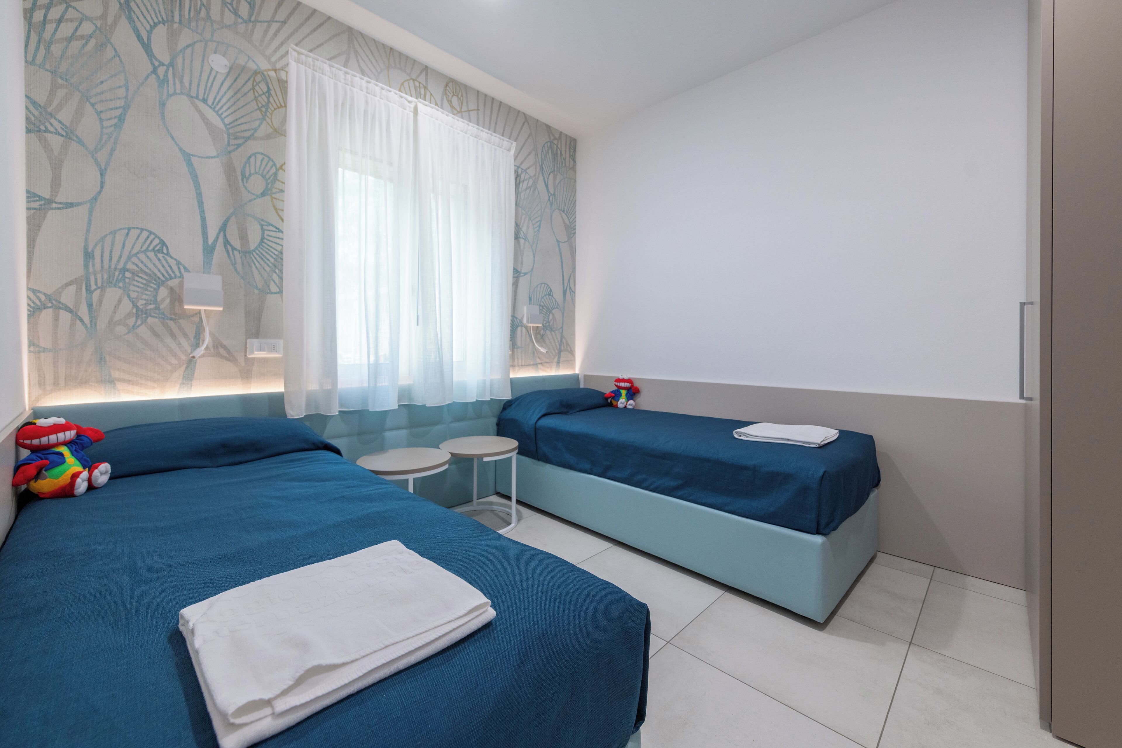 Une chambre d’hôtel avec deux lits, une petite table et un mur décoratif.