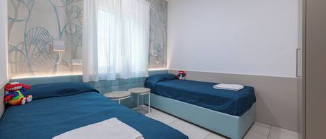 Une chambre d’hôtel avec deux lits, une petite table et un mur décoratif.