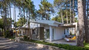 Un espace de vie extérieur moderne, doté d’un coin salon abrité, d’une petite table et d’un banc.