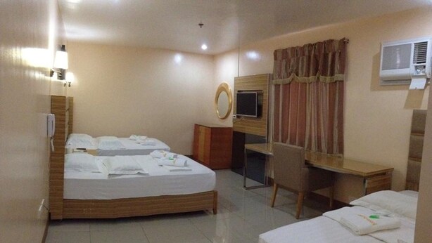 Habitación de hotel con dos camas, un escritorio, una silla, un televisor y un equipo de aire acondicionado.