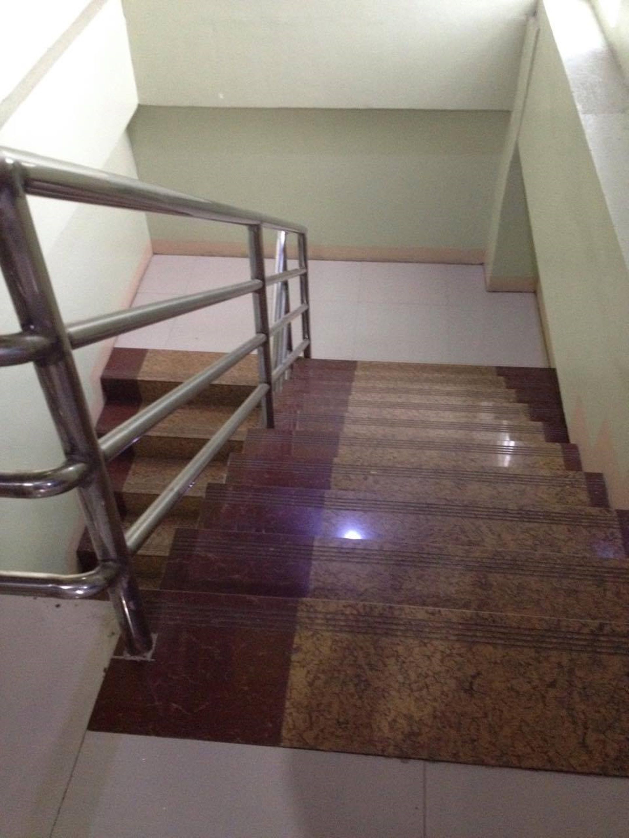 Una escalera con barandilla de metal y un piso de patrón a cuadros.