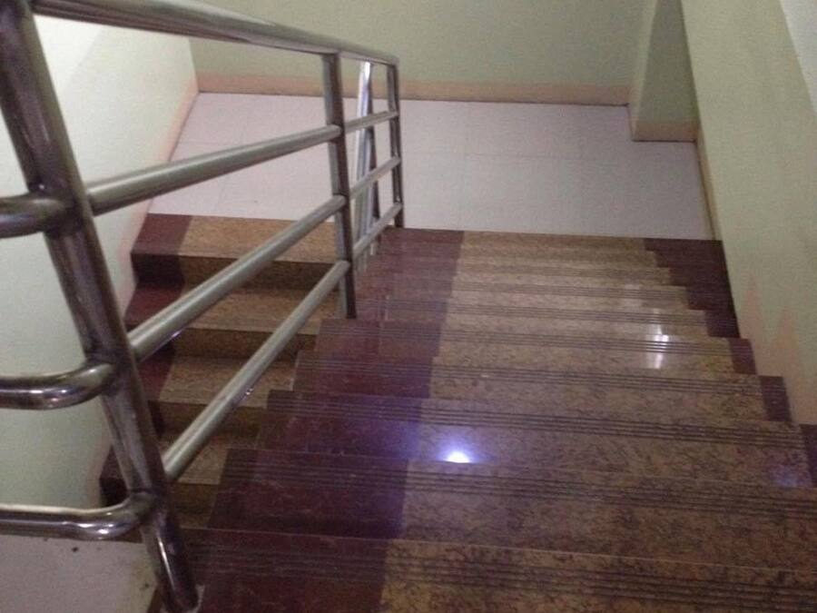 Una escalera con barandilla de metal y un piso de patrón a cuadros.