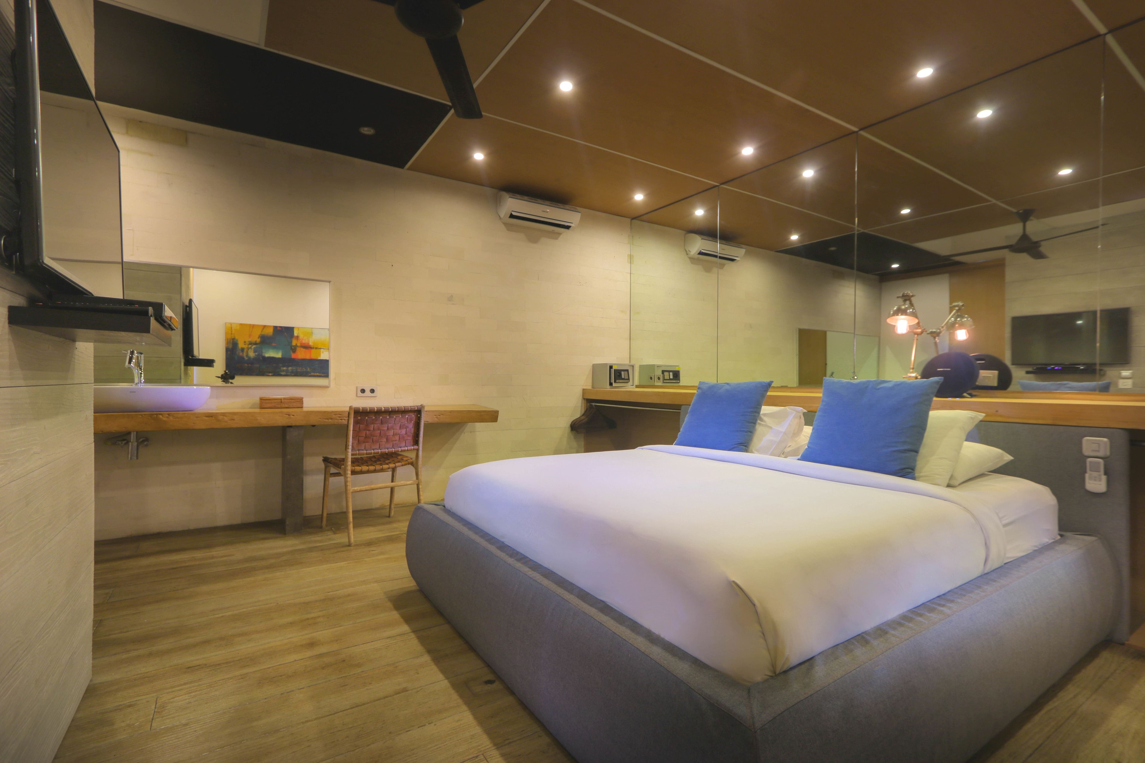 A modern hotel room with a bed, a desk with a sink, a chair, and a TV.