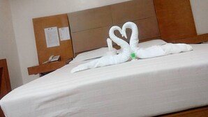 A hotel room with a bed, a wooden headboard, a nightstand with a phone, and a wall-mounted light fixture. - Asia Novo Boutique Hotel - Dumaguete (Dumaguete)