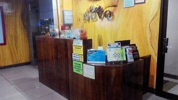 A reception desk with a wooden finish, a wall-mounted air conditioner, and several informational signs.