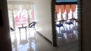 A room with a tiled floor, a large window with curtains, and a seating area with chairs and tables. - Asia Novo Boutique Hotel - Dumaguete (Dumaguete)