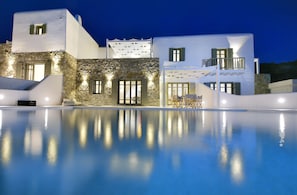 A modern building with a stone facade, a pool, and outdoor seating. - Mykonos Ark Villas (Mykonos)