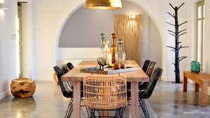 A dining area with a wooden table, wicker chairs, and a chandelier.